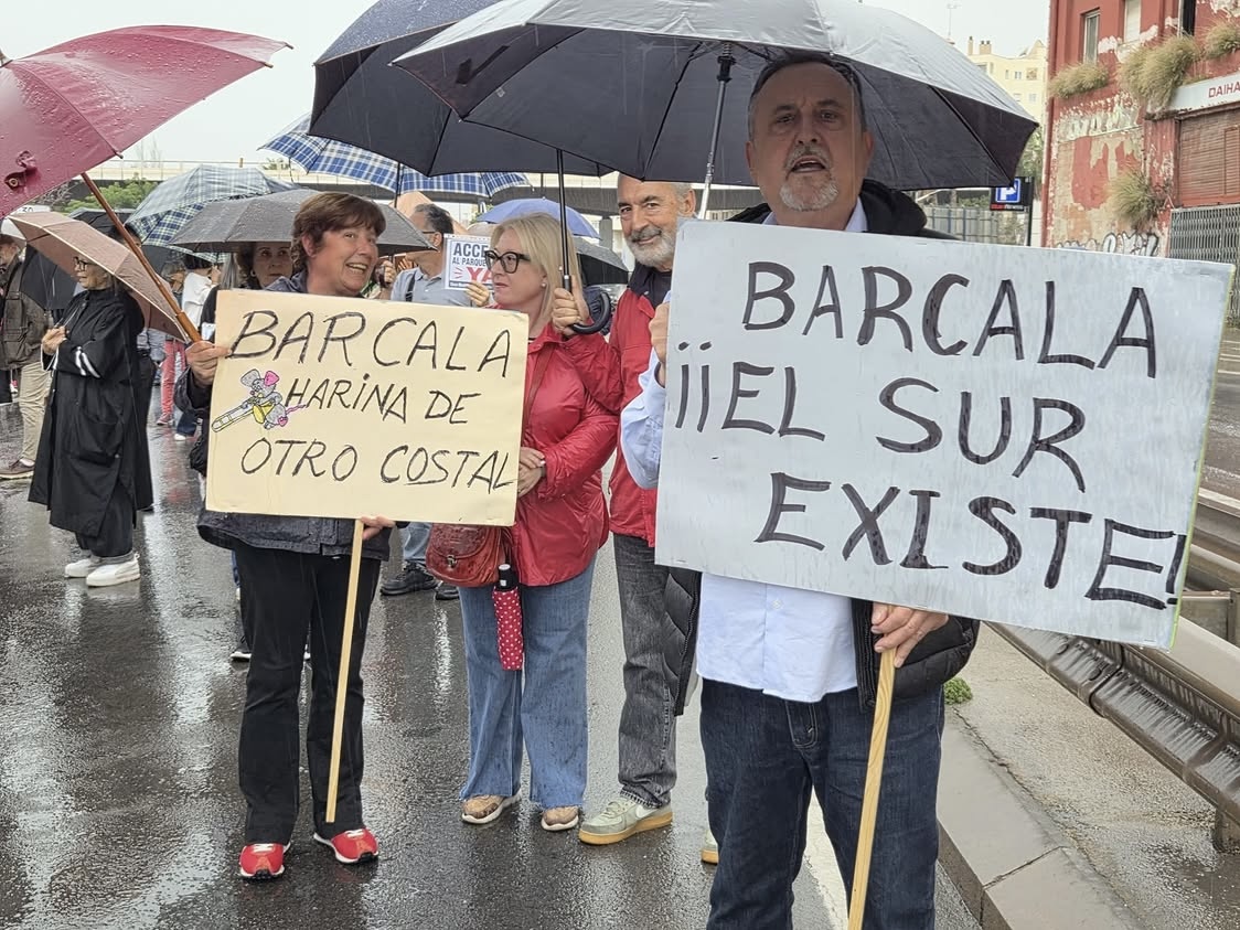 Vecinos muestran pancartas reivindicativas bajo la lluvia durante la manifestación