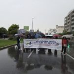 Vecinos con paraguas sostienen la pancarta de la Asociación de Vecinos Parque del Mar de Alicante durante la manifestación