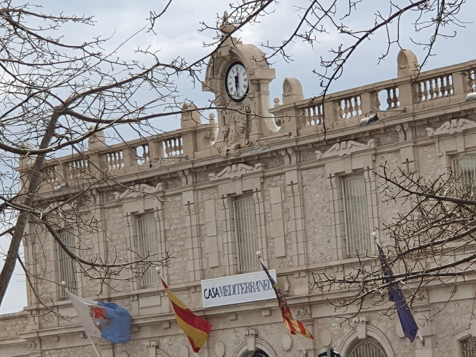 Fachada histórica de Casa Mediterráneo con el reloj, el rótulo y las banderas