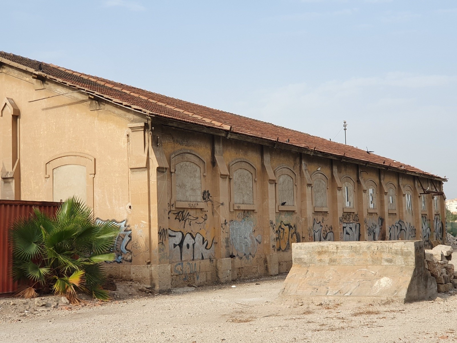 Fachada deteriorada del antiguo tinglado ferroviario con ventanas tapiadas y grafitis